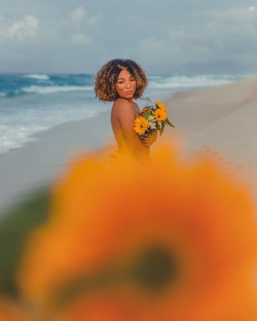 Woman Holding Flowers on the Beach