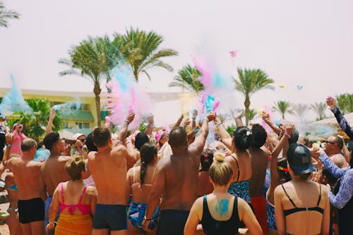 Crowd of People at a Beach Party Throwing Colorful Powder in the Air