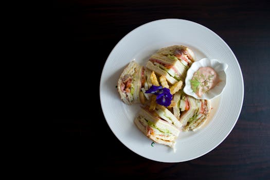Delicious clubhouse sandwich with sauce and floral garnish on a plate, perfect for food photography.