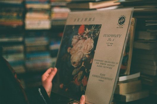 A close-up of a person holding a Brahms Symphony No. 4 vinyl record in a secondhand store in Adana, Turkey.