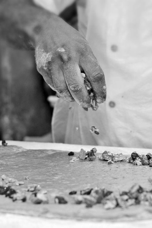 Free Chef's hand sprinkling nuts on dough in a Fes kitchen, Morocco. Black and white culinary scene. Stock Photo