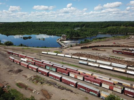Aerial shot showing a scenic train yard beside a lake in Cloquet, MN under a blue sky.
