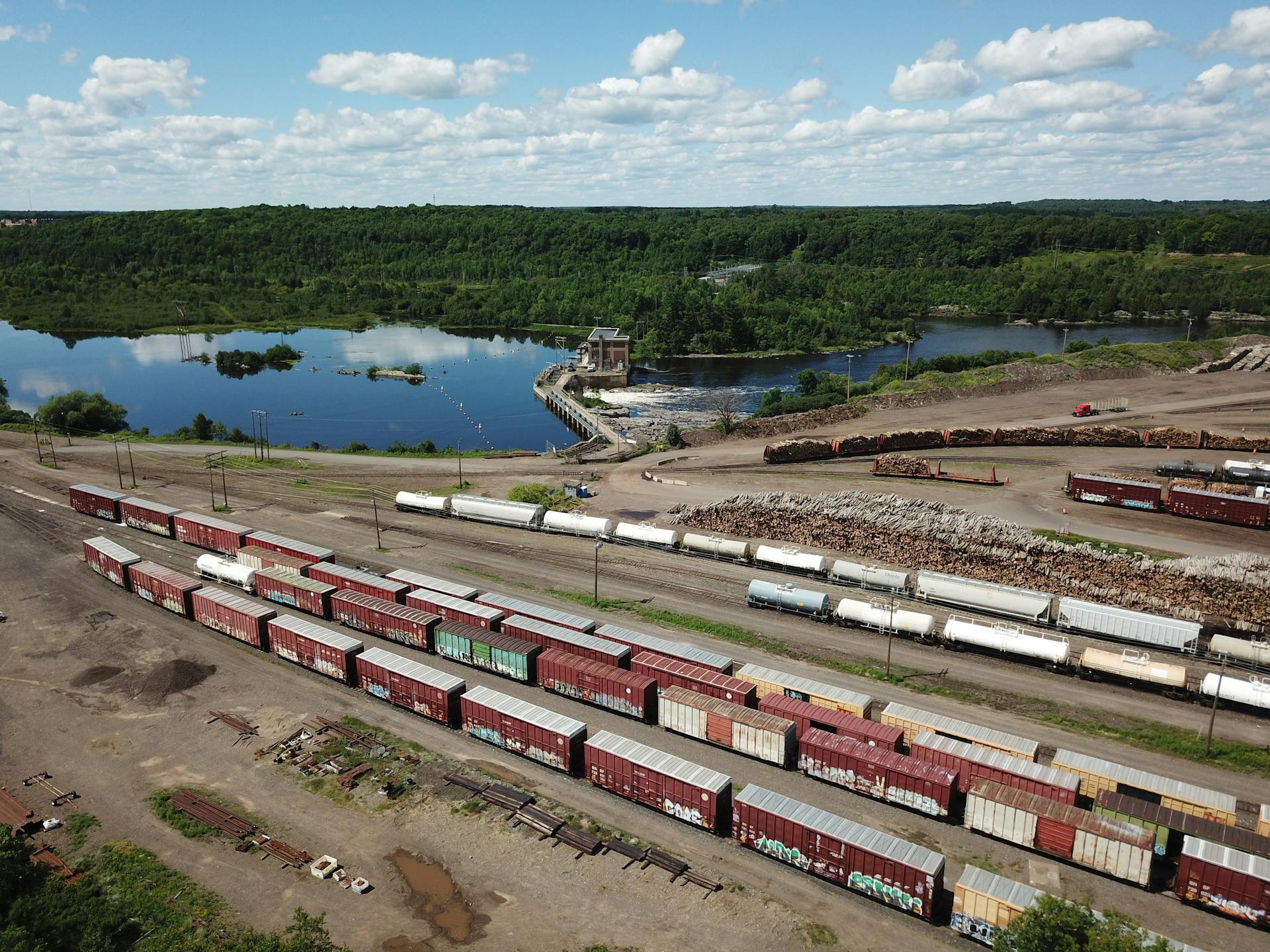 Aerial shot showing a scenic train yard beside a lake in Cloquet, MN under a blue sky.