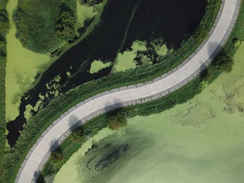Free Drone shot capturing a curved road surrounded by lush greenery and a river in Monticello, MN. Stock Photo