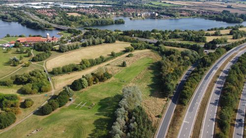 Free Aerial shot of Bletchley, England showcasing lush landscapes, a lake, and open roads. Stock Photo