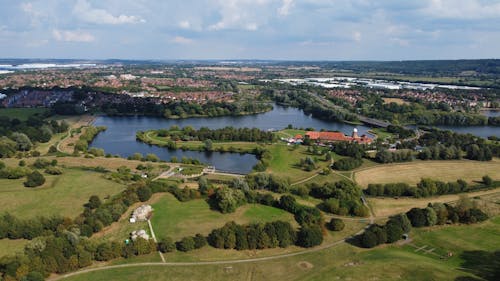 Aerial View of a Lake Surrounded by Green Grass Field in Simpson, England, United Kingdom