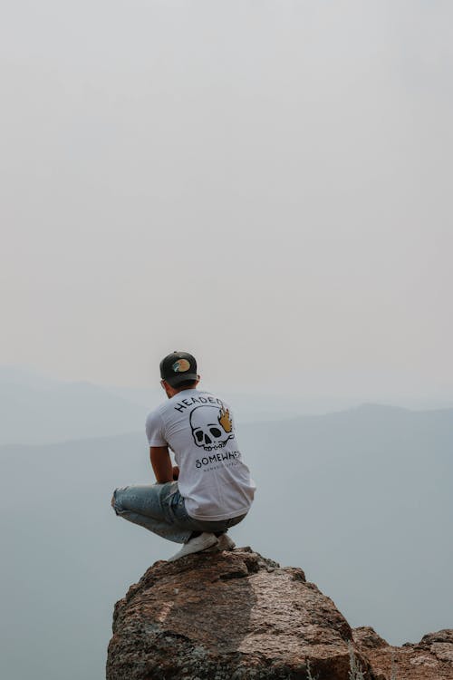 A Back View of a Man Sitting on the Rock