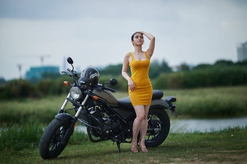 Woman in Yellow Dress Standing Beside a Motorcycle
