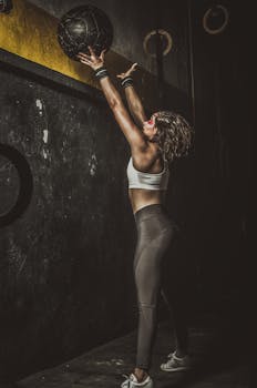 Sporty woman in gym throwing medicine ball, strong workout focus.