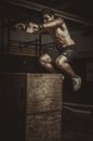 Topless Man in Black Shorts Sitting on Brown Wooden Box
