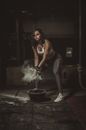 Woman in Black Tank Top and Black Pants Sitting on Floor With White Smoke