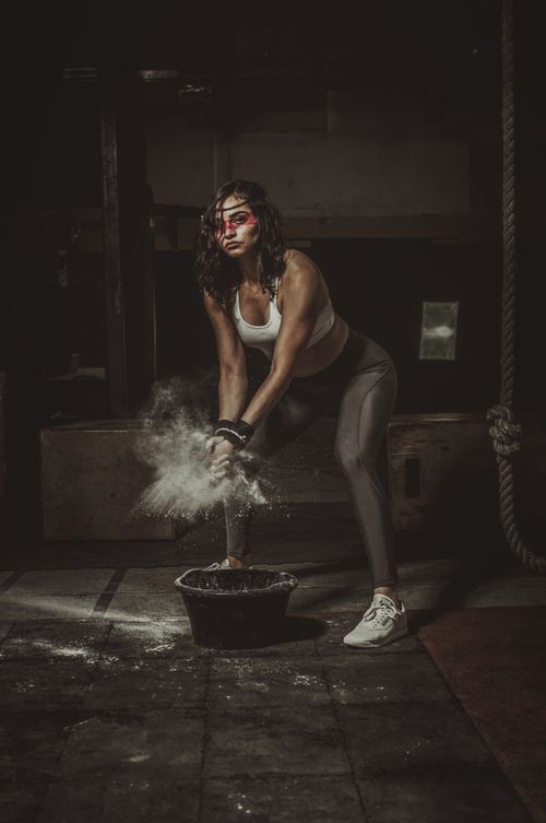 Free Fit woman in sportswear applying chalk on hands before a workout, showcasing strength and determination. Stock Photo