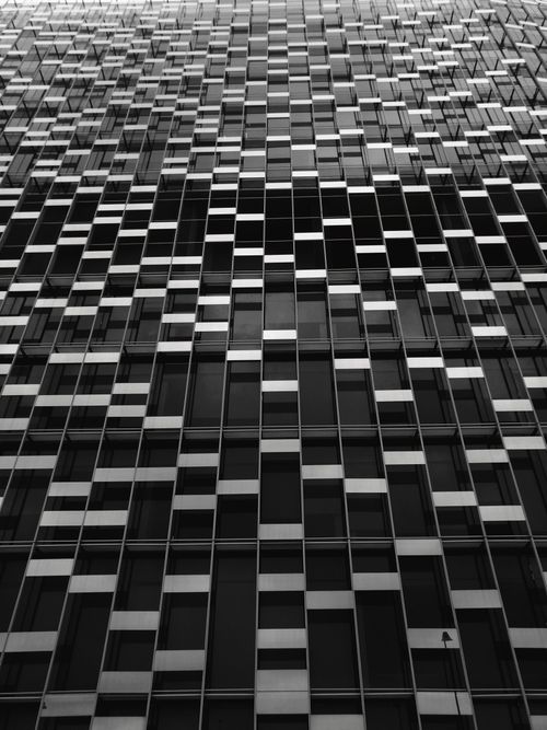 Free Black and white photo showcasing a geometric facade on a modern high-rise building. Stock Photo