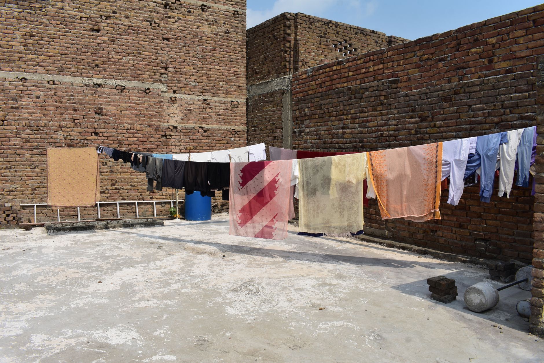 Laundry hanging out to dry on a brick rooftop under a sunny sky, showcasing urban life.