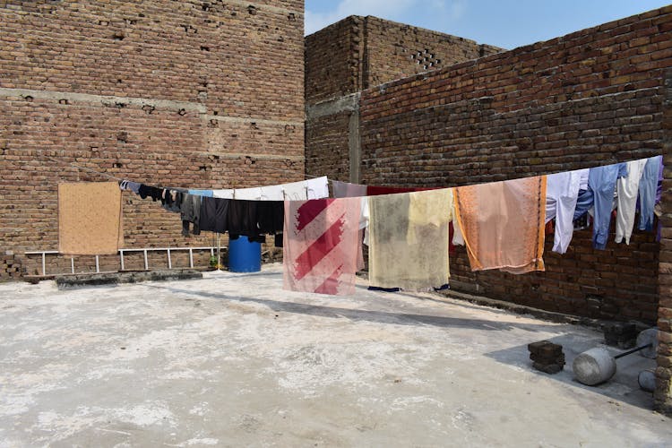 Clothes Hanging Near Brick Wall 