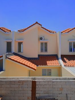 Charming row of townhouses with terracotta roofs and clear blue sky, showcasing suburban architecture. - Fotografer Sidoarjo