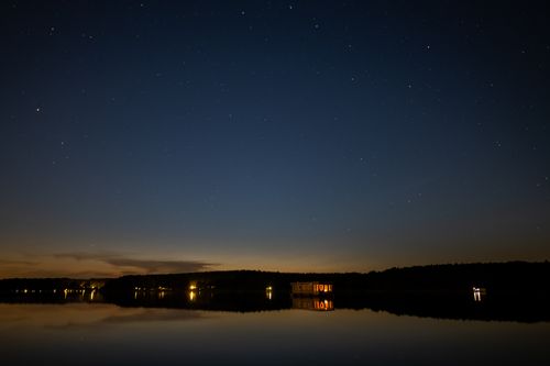 Free Starry night sky reflecting over a tranquil lake in Rheinsberg, Germany. Stock Photo