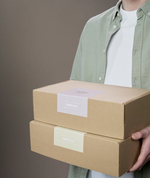 Free A Person Carrying Cardboard Boxes with Labels Stock Photo