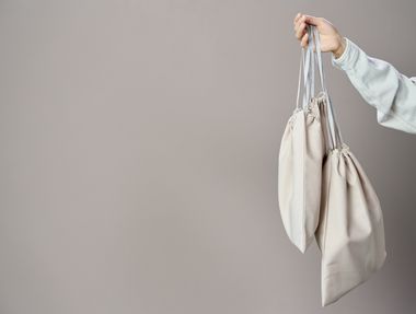 Hand holding folded canvas bags, photo by Ron Lach on Pexels