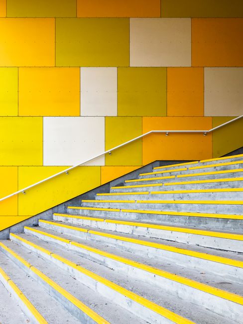 Bright yellow staircase with geometric wall pattern in urban setting, Oslo, Norway.