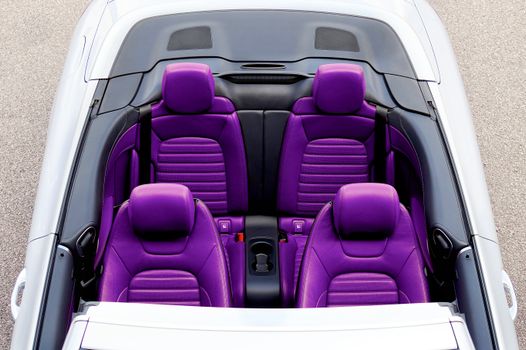 Top view of a luxurious convertible car featuring vibrant purple leather seats.