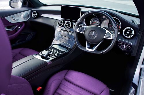 Free Interior view of a Mercedes Benz showing luxury steering wheel and purple leather seats. Stock Photo