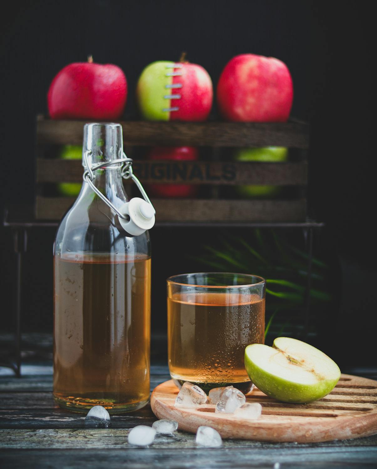 apple cider vinegar and a green apple on wooden board