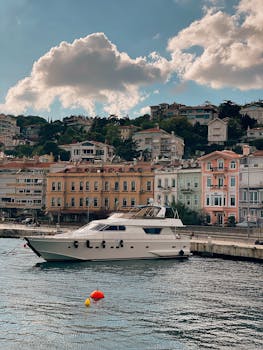 Luxury yacht docked at a colorful waterfront, showcasing charming architecture under a partly cloudy sky.