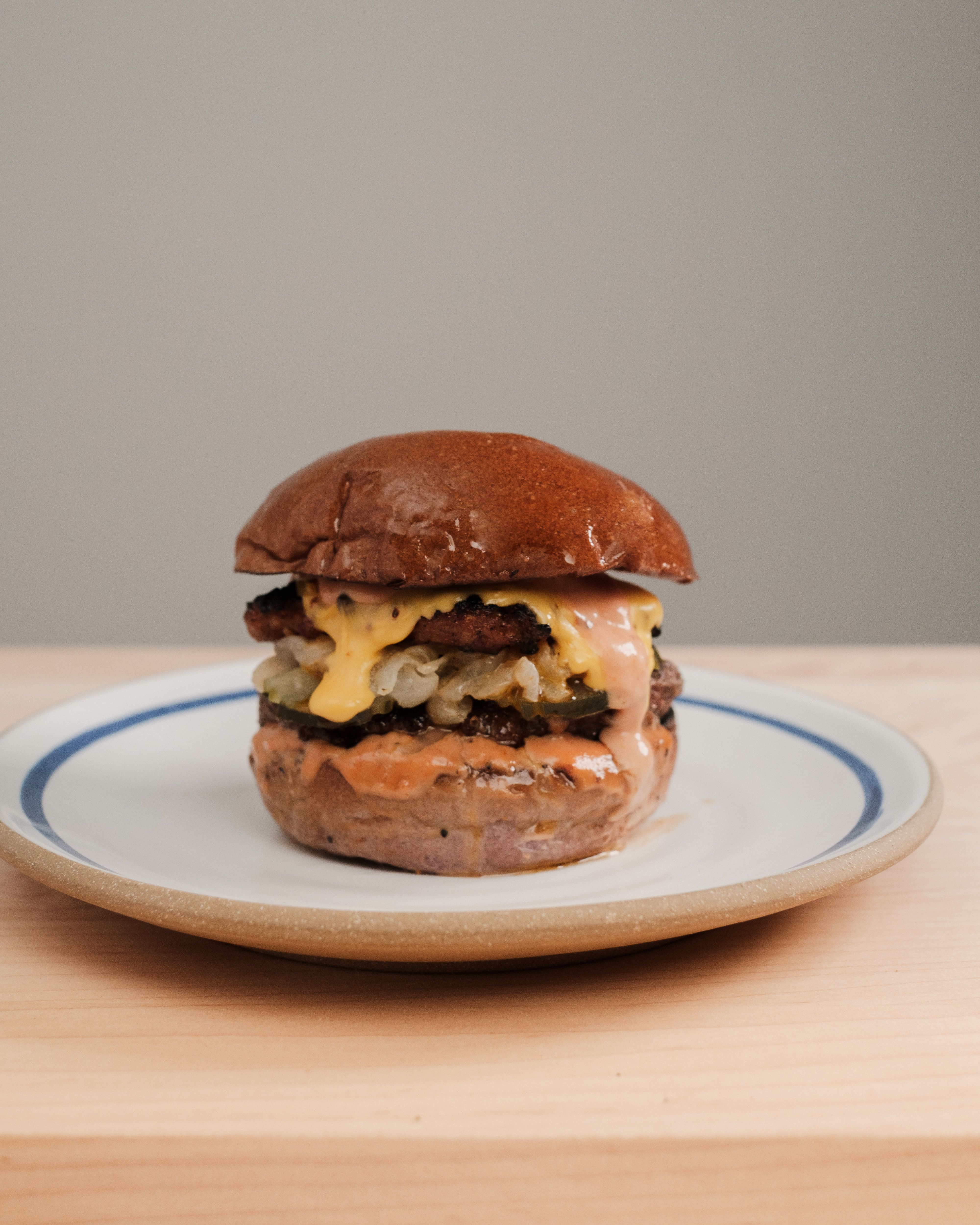 Mouthwatering cheeseburger with melted cheese on a rustic ceramic plate. Perfect for food lovers.