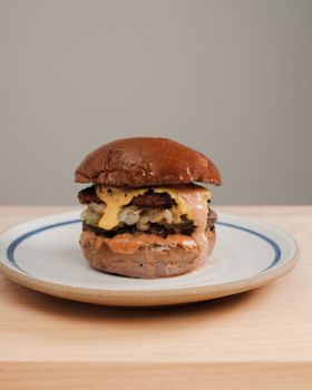 Mouthwatering cheeseburger with melted cheese on a rustic ceramic plate. Perfect for food lovers.