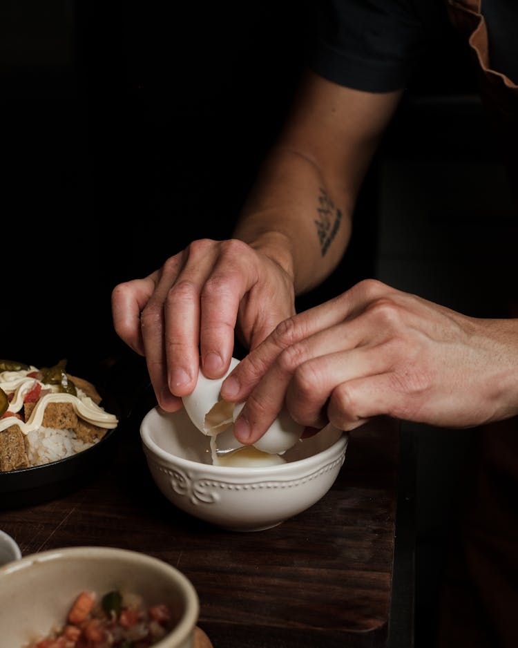 Close Up On Man Breaking Egg In Pot