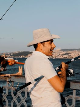 A man in a white hat fishing by the sea on a sunny day, showcasing leisure and relaxation.