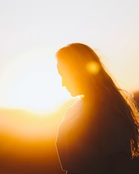 A woman with long hair silhouetted against a bright, sunlit background.