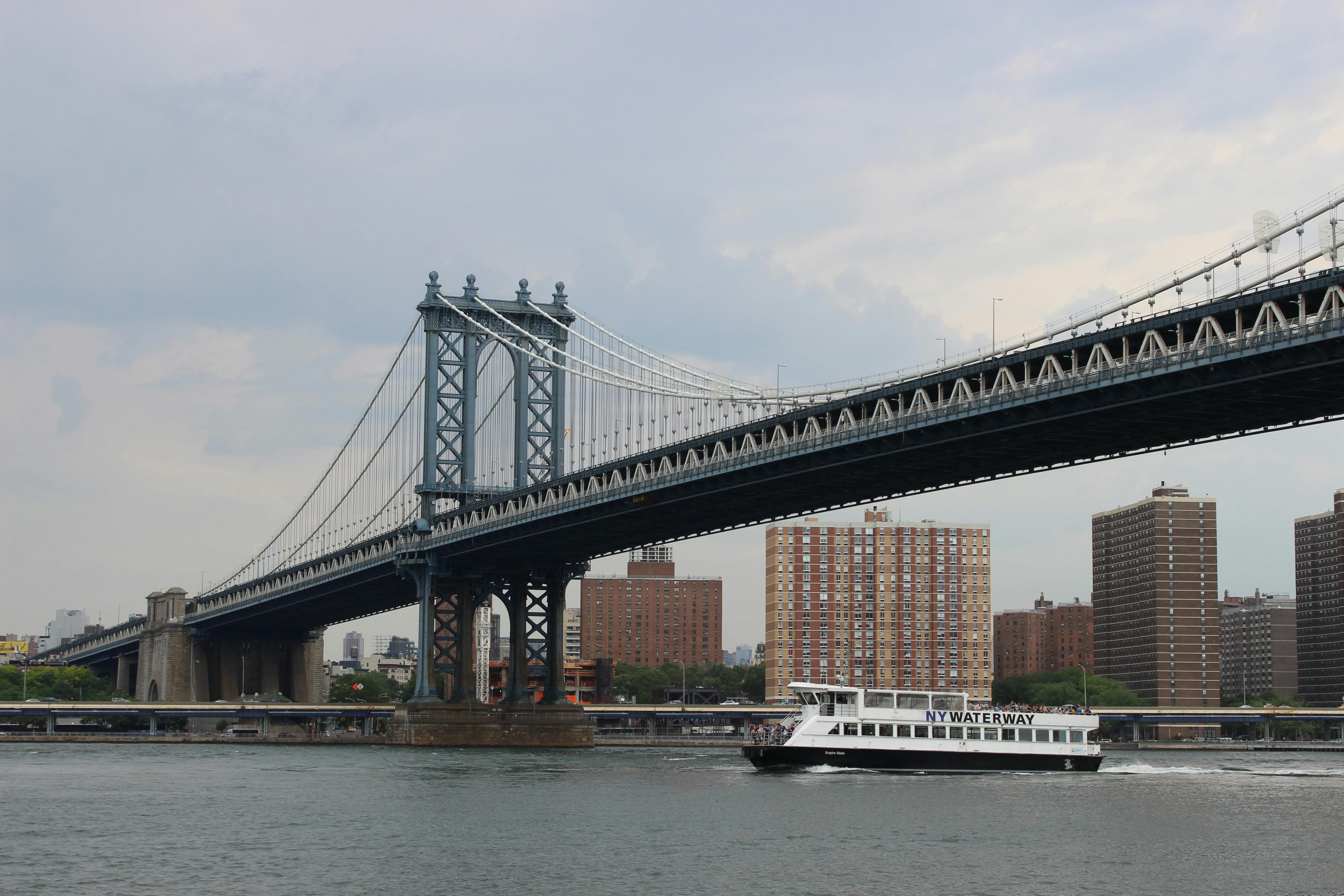 View of Manhattan Bridge spanning the East River with an NY Waterway ferry in New York City.