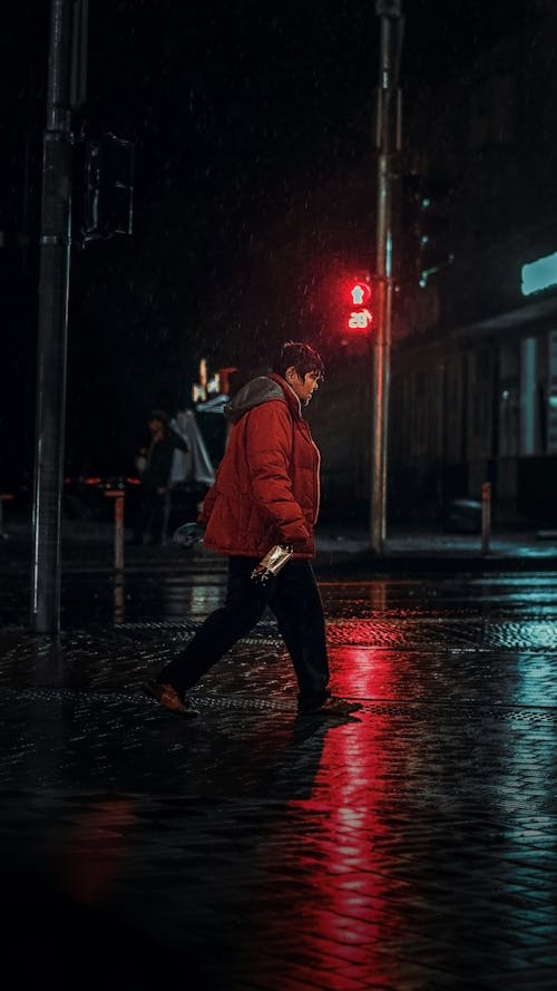 Man in Red Jacket Walking near a Post