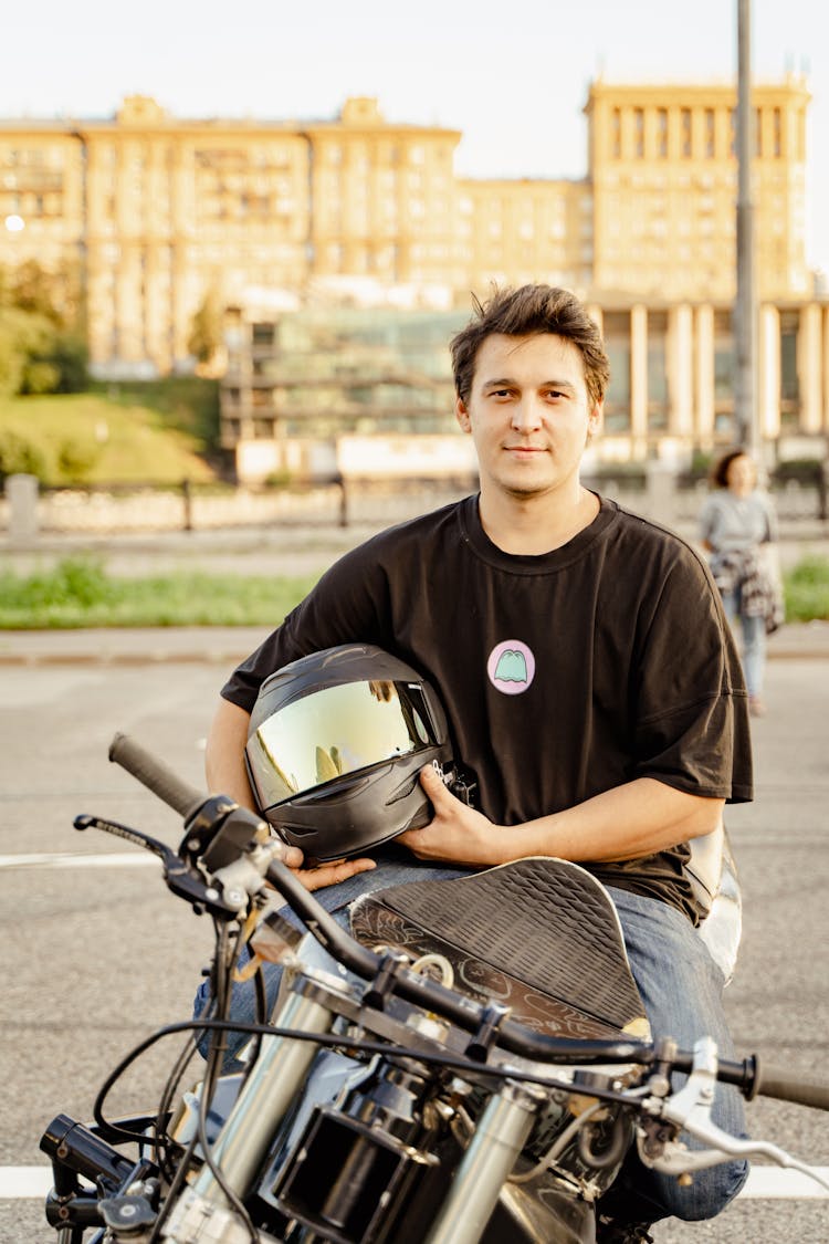 Man Sitting On Motorbike Holding Helmet