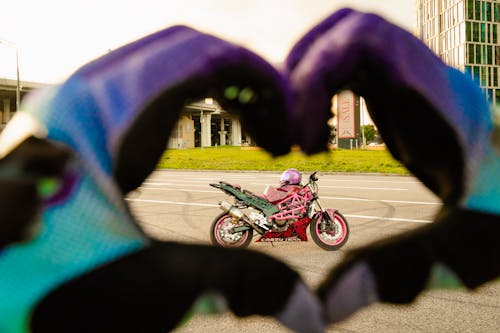 Free A Person Wearing Gloves Giving a Heart Hand Gesture on a Motorbike Stock Photo