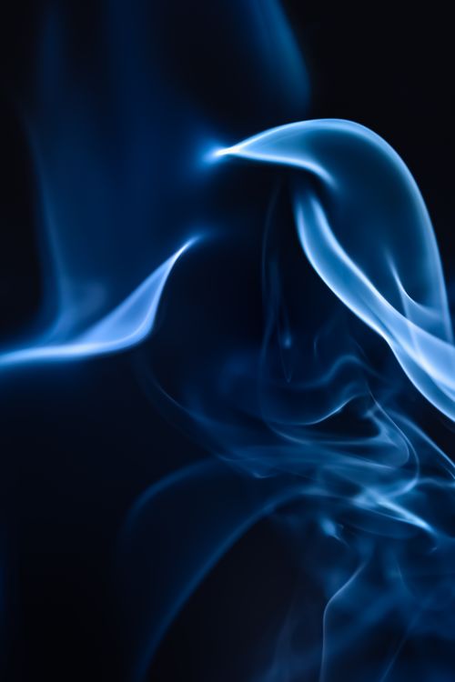 Free A mesmerizing close-up of blue smoke swirling against a dark black background, creating a dreamy abstract pattern. Stock Photo