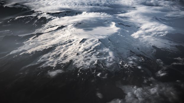 A stunning aerial view capturing the dramatic snow-capped mountain landscape of Iceland under a cloudy sky.