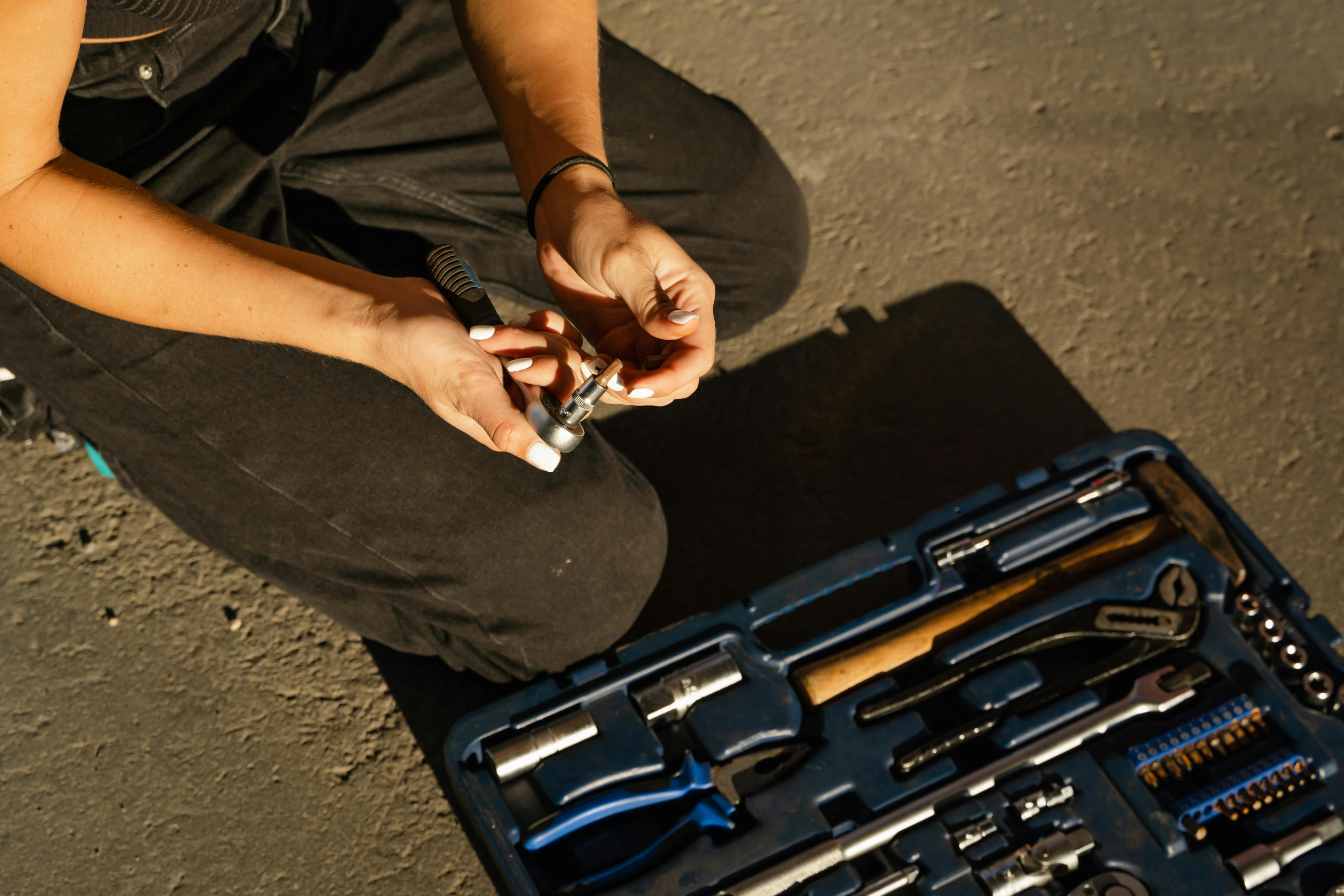 Close-up of a person selecting a tool from a repair kit outdoors. Perfect for DIY or mechanical concepts.