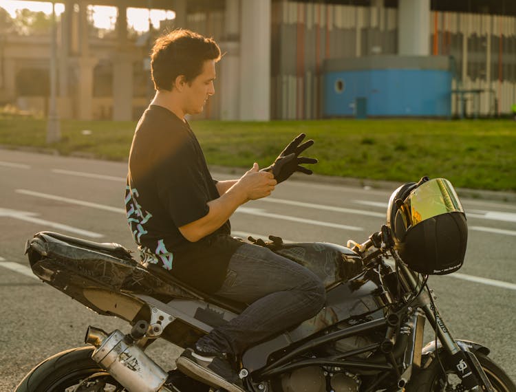 Close-Up Shot Of A Man Putting On Gloves While Sitting On A Motorcycle