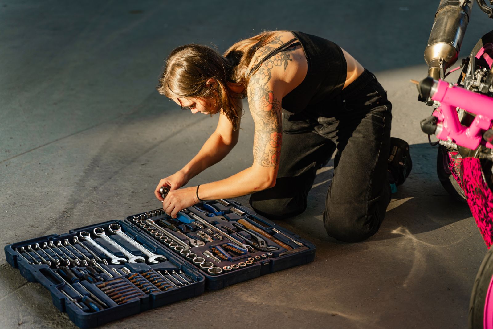 Jeune femme tatouée organisant des outils près de sa moto