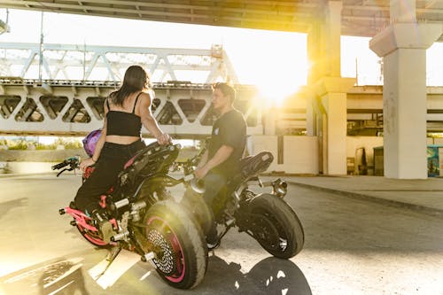 Man and Woman Sitting on Motorcycles during Sunset