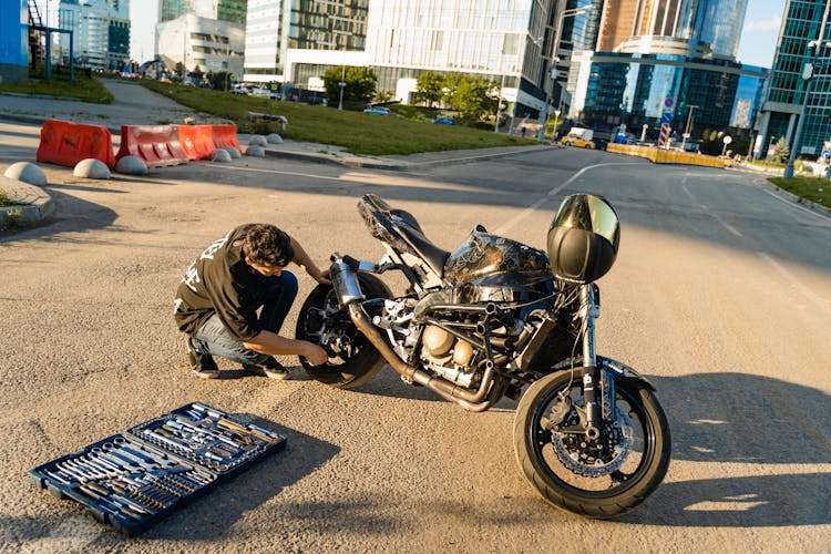 Man Repairing His Motorcycle On Road 