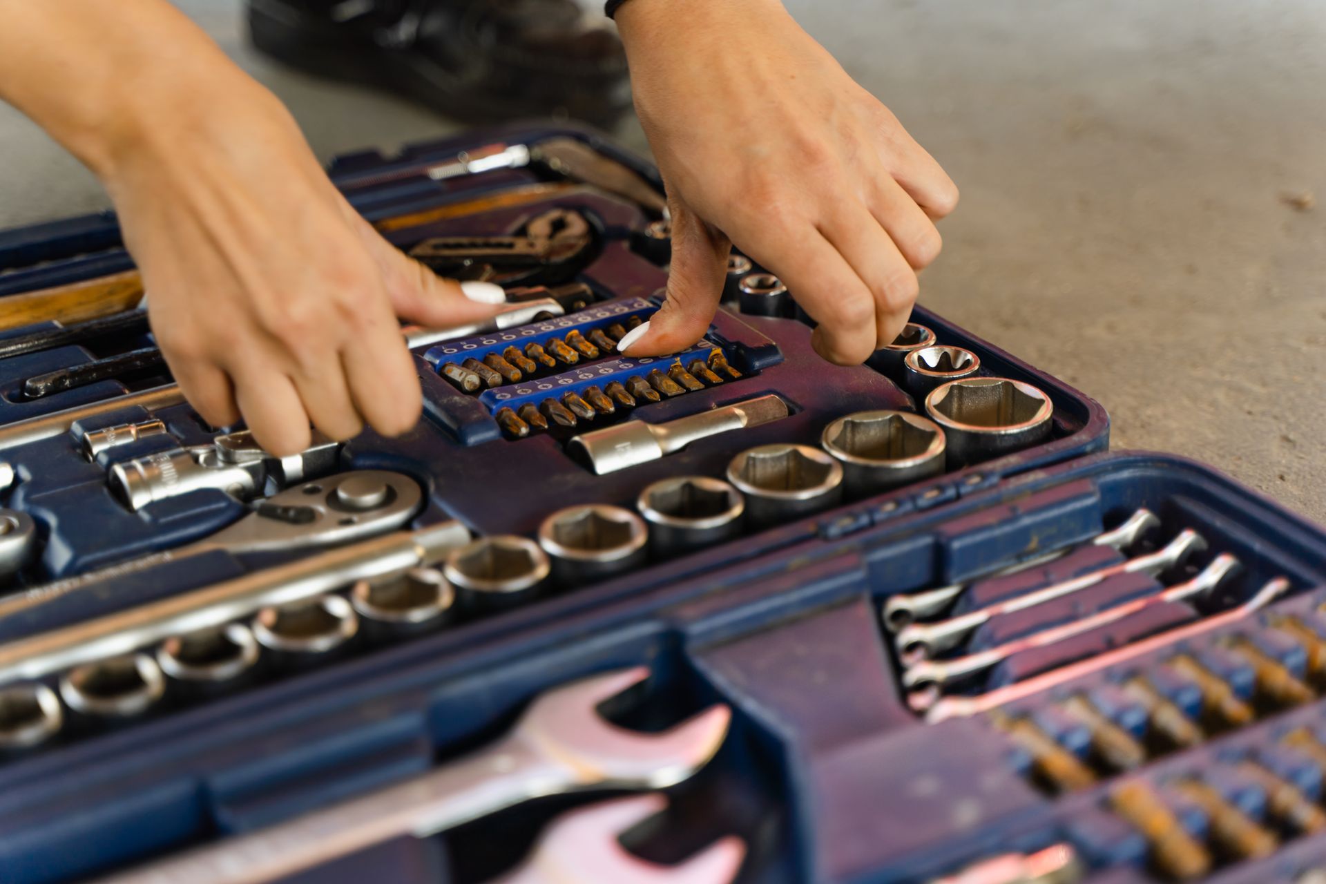 Hands selecting tools from a well-organized toolbox