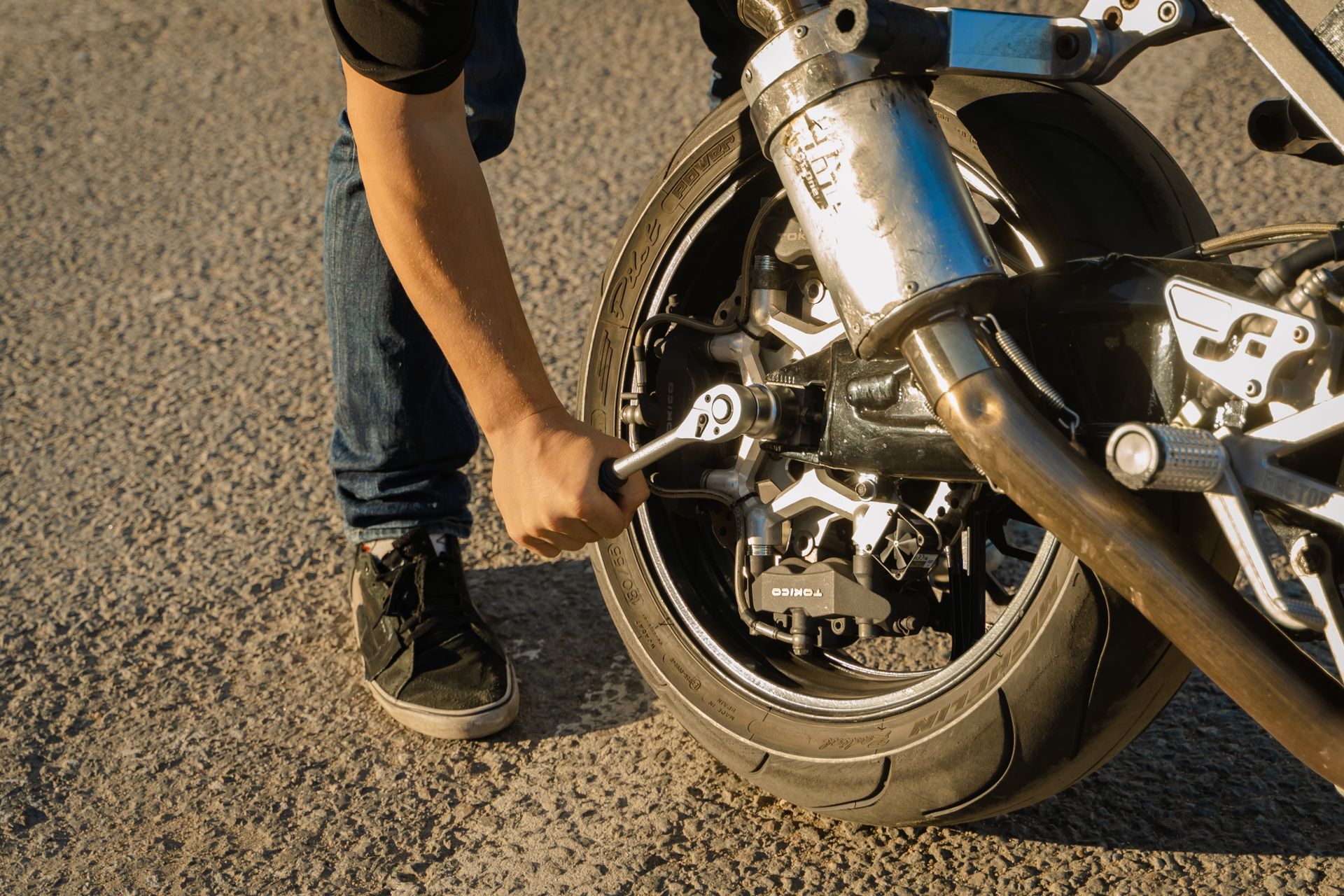 Hand of a Person Holding a Wrench on a Motorcycle Wheel