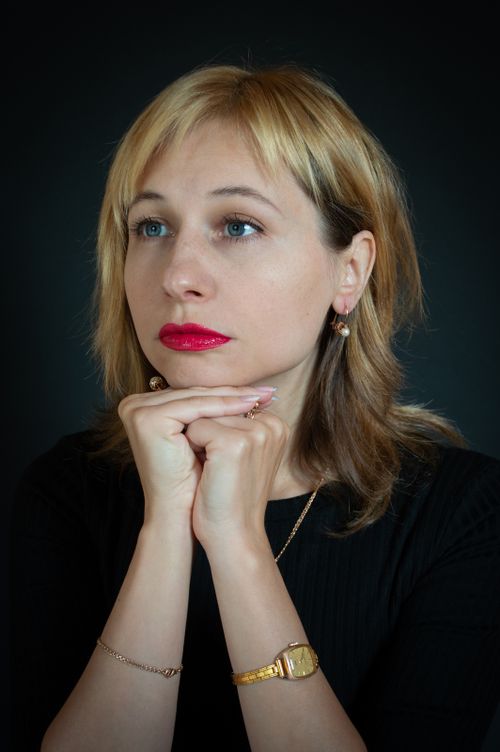 Free Close-up portrait of a thoughtful woman with blonde hair and red lipstick in a studio setting. Stock Photo