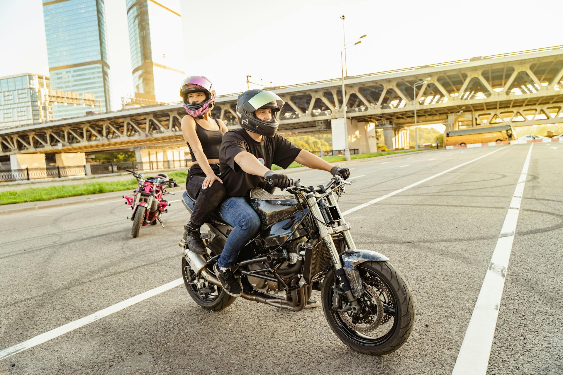 A couple riding a motorcycle through an urban area on a sunny day.