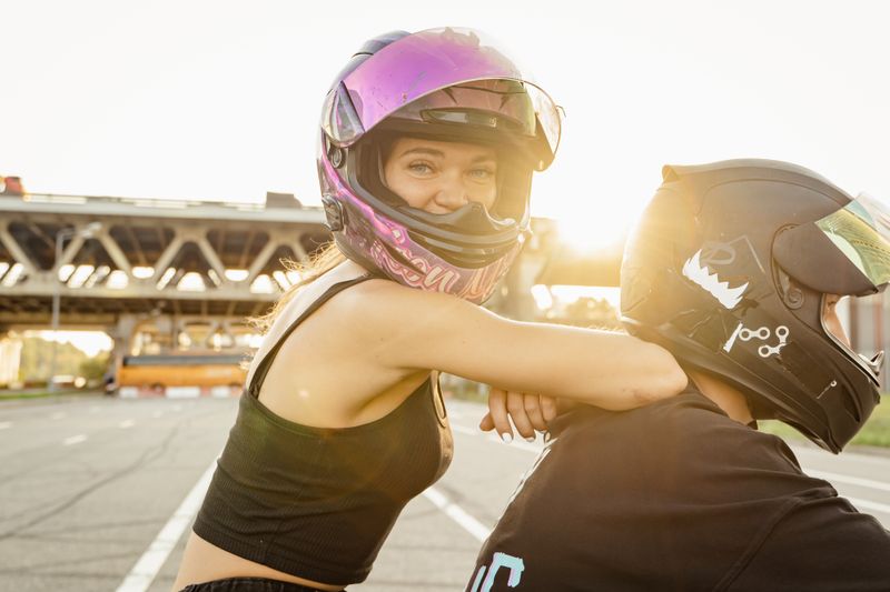 Smiling woman in a helmet enjoying a sunset ride on a motorcycle