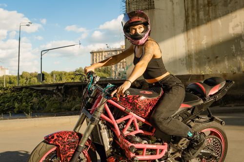 Free Woman wearing a helmet riding a stylish customized motorcycle under a bridge. Stock Photo